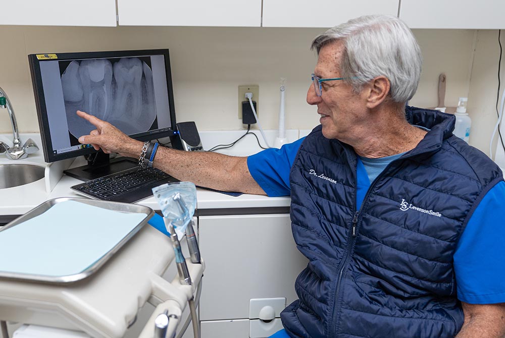 Dr. Stanley Levenson points to a dental image on the screen of a monitor