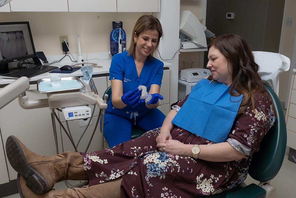Dr. Jessy Ajram shows samples of clear aligners to a female patient